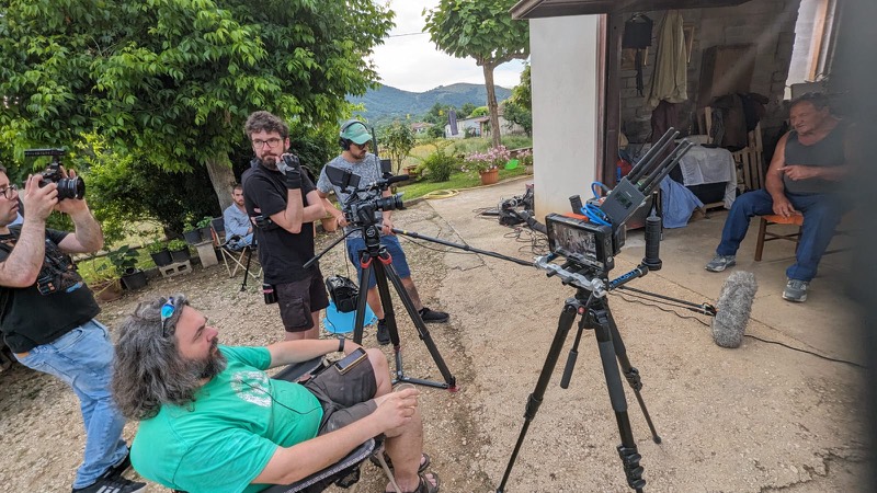 Il set di Avvino nell'aia di una cascina: due macchine da presa, la troupe, il contadino seduto sulla destra