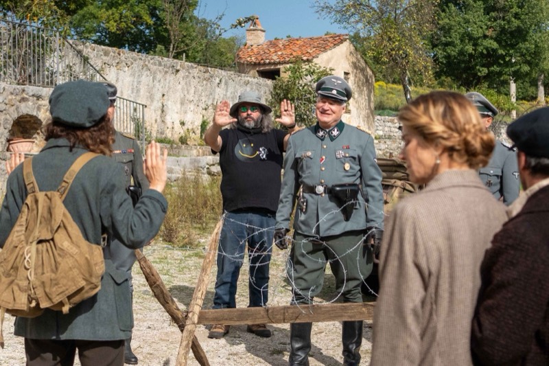 Gianni Aureli alza le mani a incorniciare l'inquadratura davanti a un attore in divisa tedesca, sul set